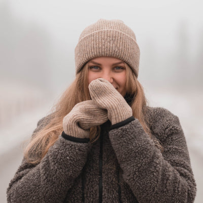 Sui Ava Beanie Sheepskin, lue i ullblanding i beige farge vist på jente utendørs